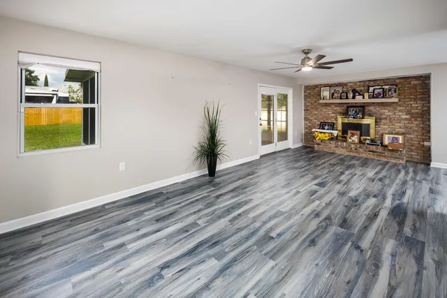 a view of an empty room with window and wooden floor