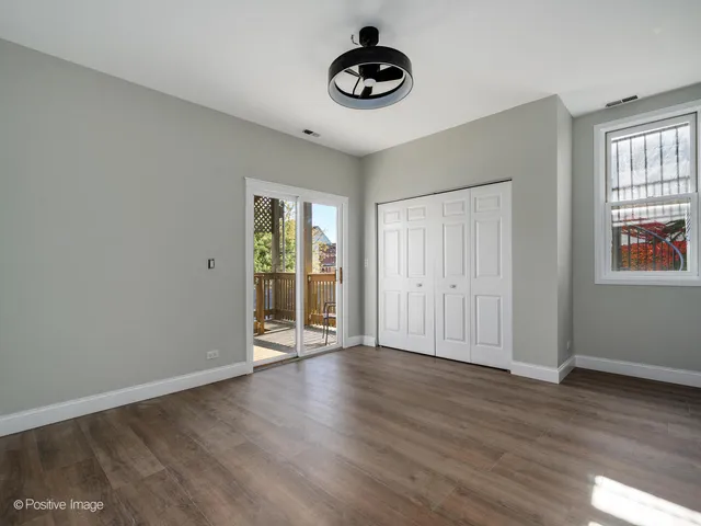 a view of an empty room with wooden floor and windows