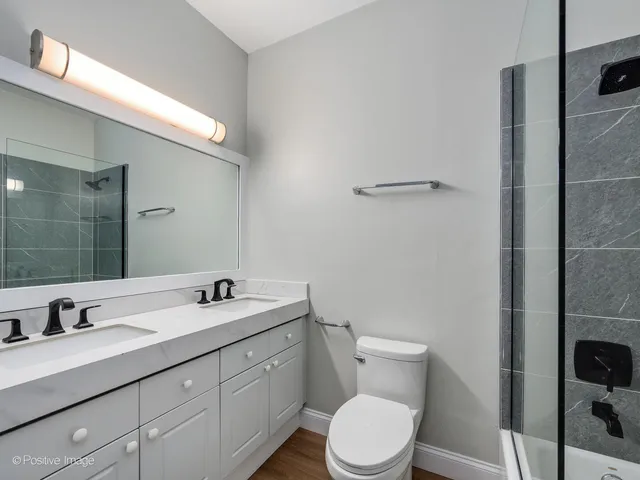 a bathroom with a double vanity sink toilet and a mirror