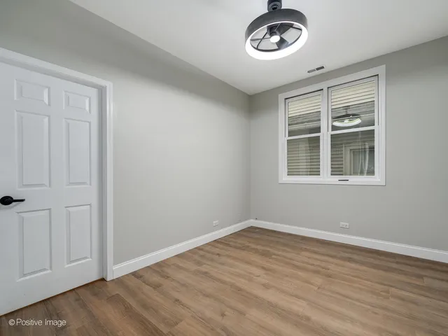 a view of an empty room with a window and hardwood floor