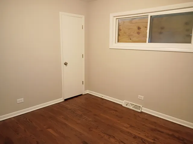 an empty room with wooden floor and window