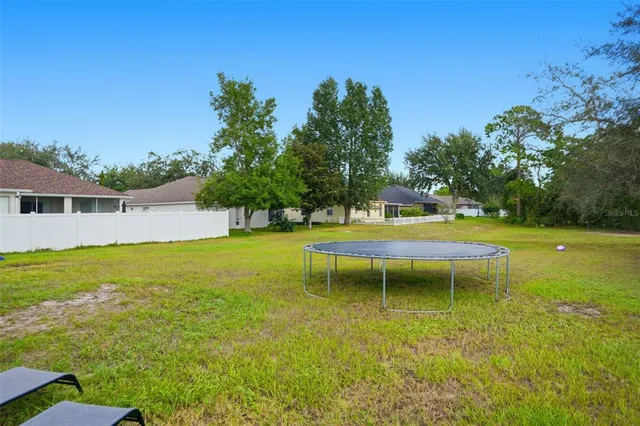 a view of a swimming pool with a bench and trees in the background