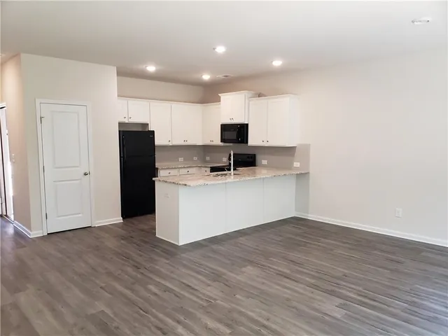 a view of kitchen with granite countertop cabinets and refrigerator
