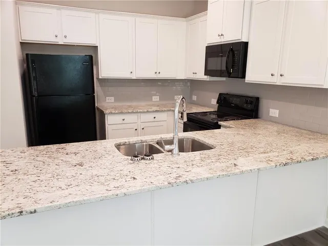 a kitchen with granite countertop a refrigerator sink and stove