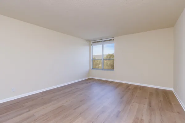 a view of an empty room with wooden floor and a window