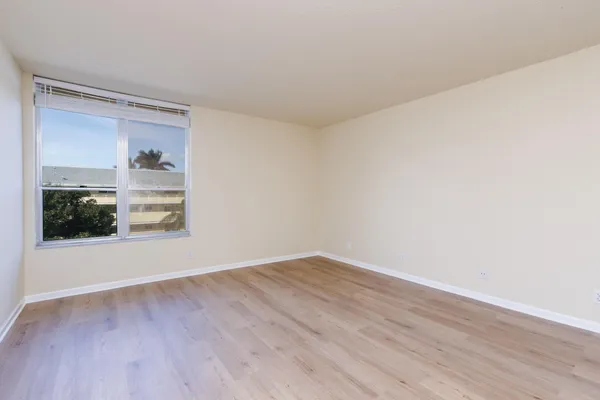 a view of an empty room with wooden floor and a window