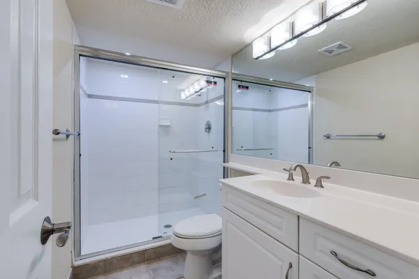 a bathroom with a shower sink vanity mirror and toilet