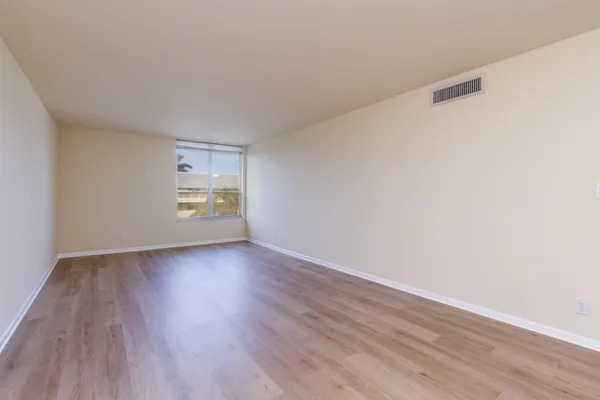 a view of an empty room with a window and wooden floor