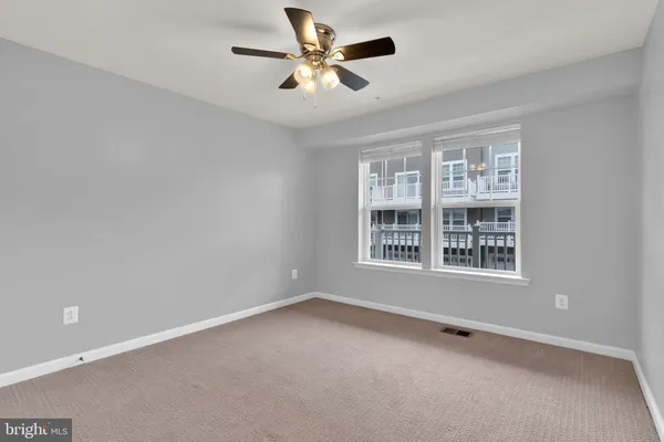 an empty room with chandelier fan and windows
