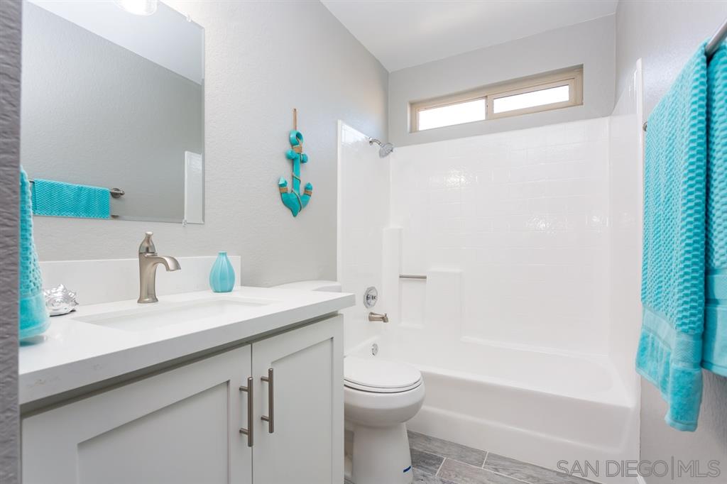 265 Argus Way Oceanside, CA 92057 - Photo 23 of 24 a bathroom with a granite countertop sink a toilet a mirror a vanity and shower