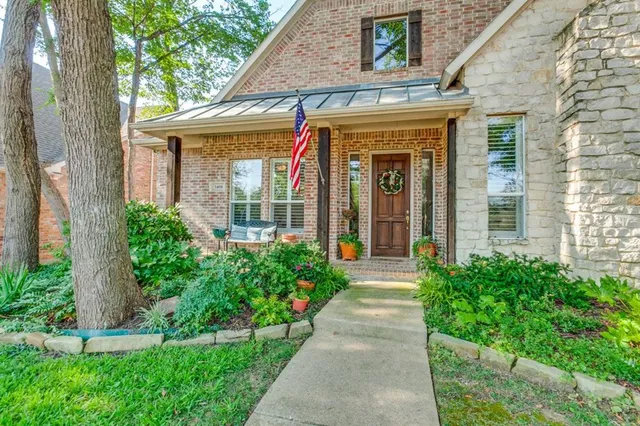 a view of a house with potted plants and a large tree