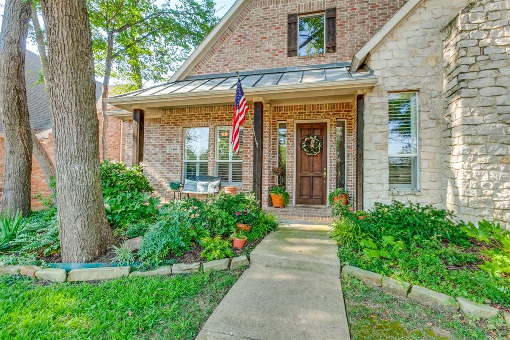 a view of a house with potted plants and a large tree