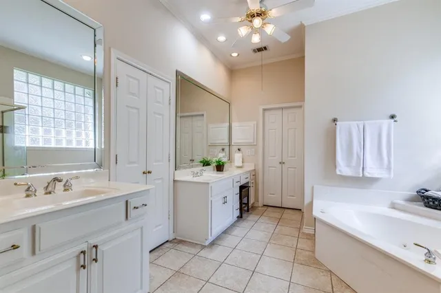 a spacious bathroom with a double vanity sink mirror and bathtub