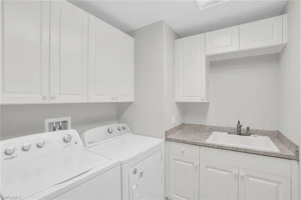 a utility room with sink dryer and cabinets