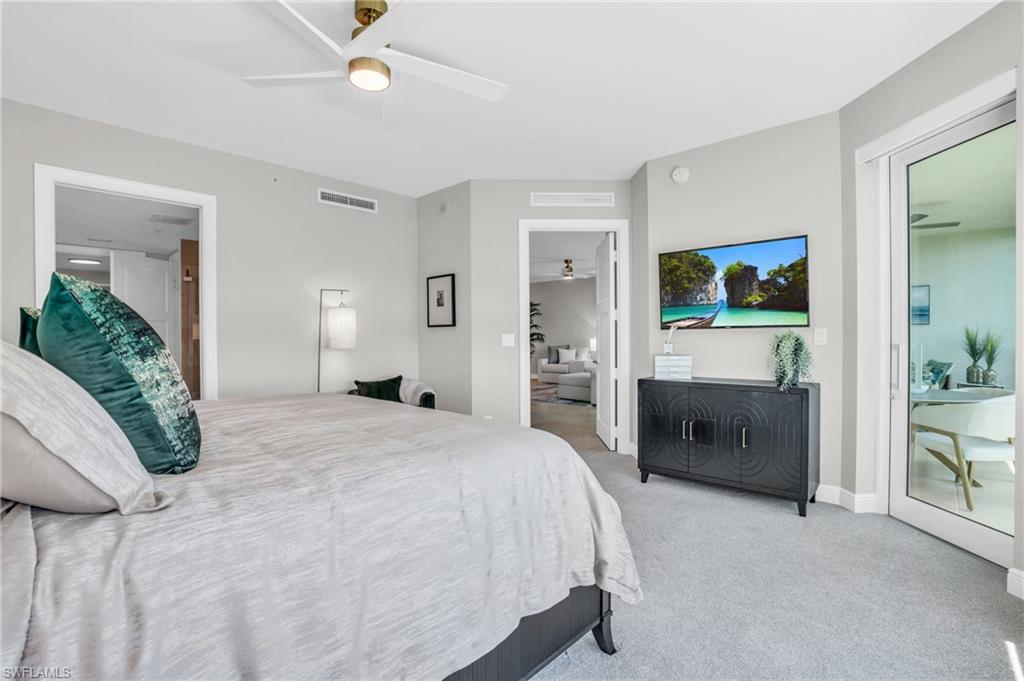 265 Indies Way, Unit 1404 Naples, FL 34110 - Photo 26 of 43 a bedroom with a bed and a chandelier