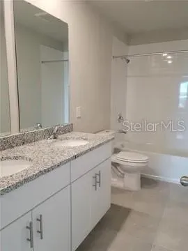 a bathroom with a granite countertop toilet sink and mirror