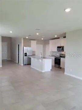 a large white kitchen with stainless steel appliances cabinets a sink and a stove