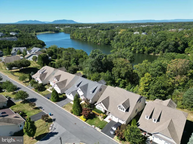 an aerial view of a house with yard and trees in the background