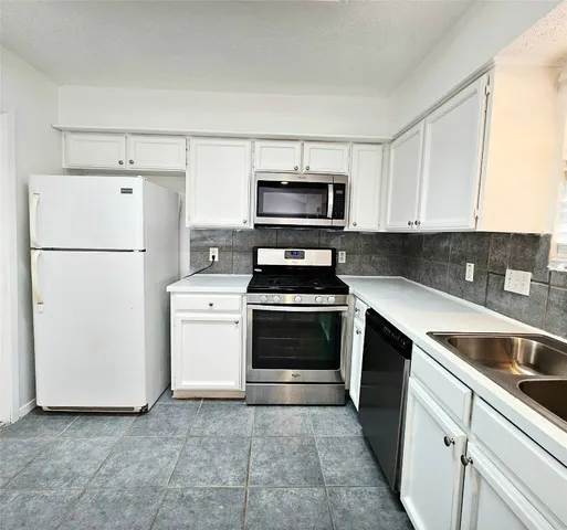 a kitchen with appliances a sink and a counter top space