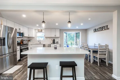 a kitchen with stainless steel appliances a table chairs refrigerator and microwave