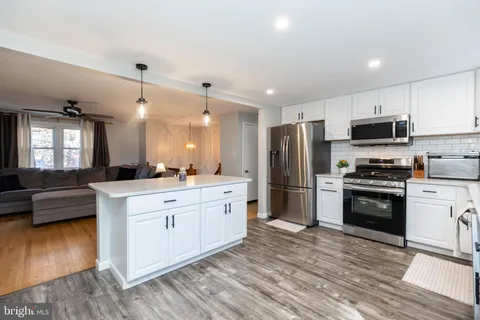 a large kitchen with stainless steel appliances a stove a sink dishwasher a refrigerator and a oven with wooden floor