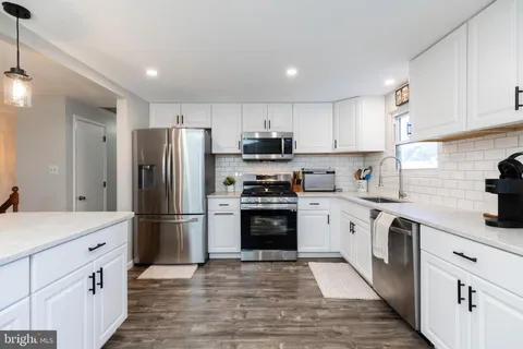 a kitchen with granite countertop a refrigerator stove and sink