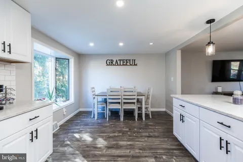 a open kitchen with stainless steel appliances granite countertop a stove top oven a sink dishwasher a dining table and chairs with wooden floor