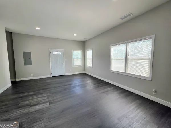 an empty room with wooden floor and windows