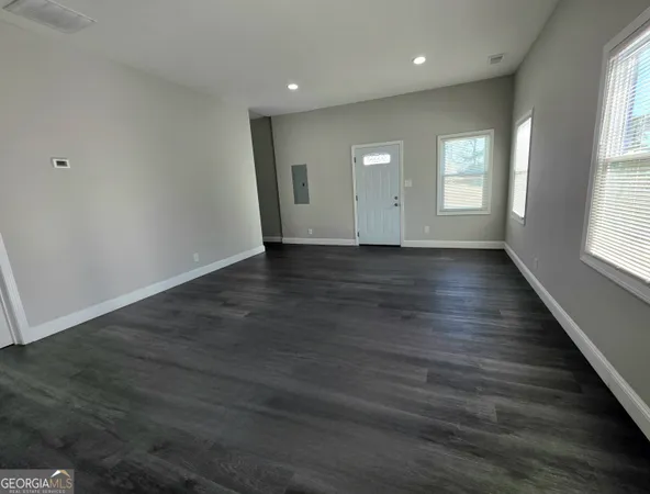an empty room with wooden floor and windows