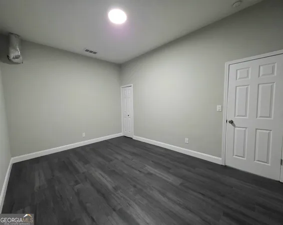 a view of an empty room with wooden floor and closet