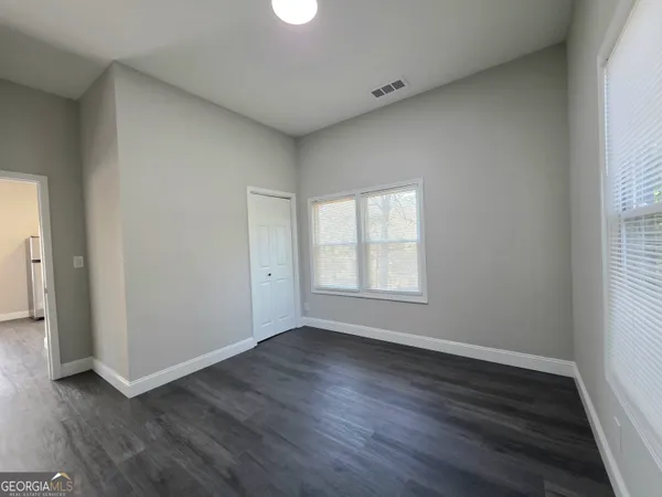 an empty room with wooden floor and windows