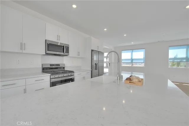 a kitchen with stainless steel appliances granite countertop a stove a sink and a refrigerator with wooden floors