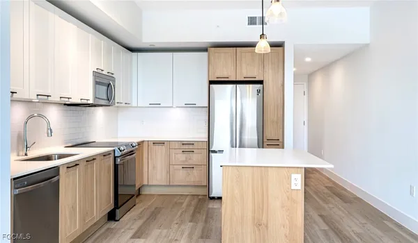 a kitchen with stainless steel appliances granite countertop a refrigerator a sink dishwasher a stove with wooden cabinets