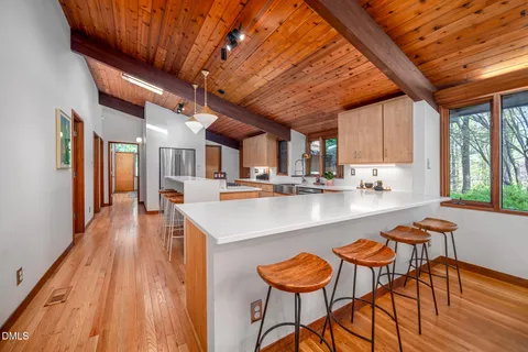 a kitchen with stainless steel appliances granite countertop a table chairs and a wooden floors