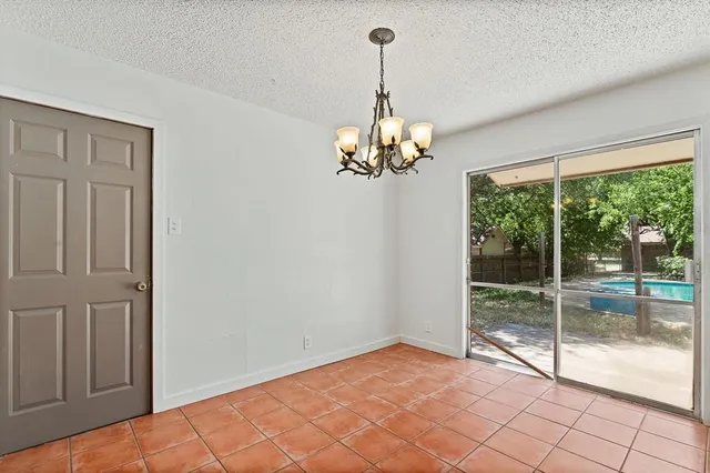 an empty room with chandelier fan and windows
