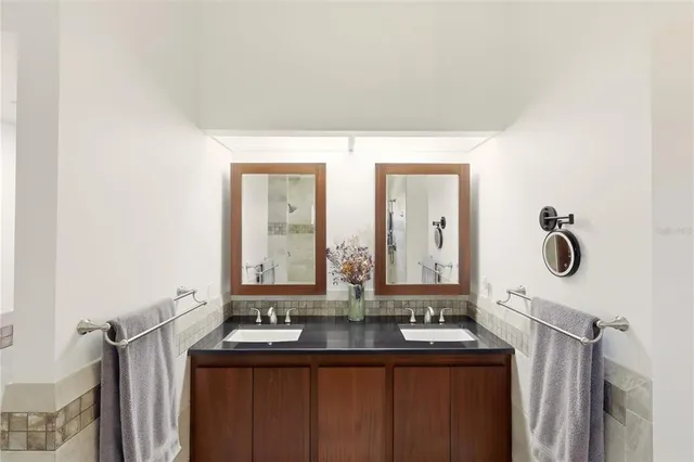 a bathroom with a double vanity sink and mirror with window
