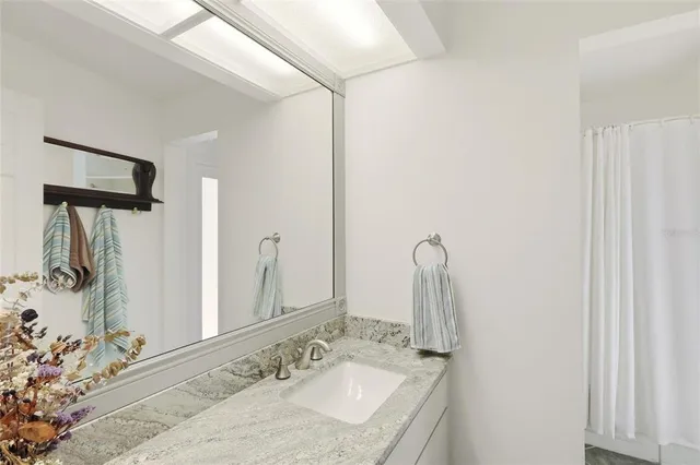 a bathroom with a granite countertop sink and a mirror