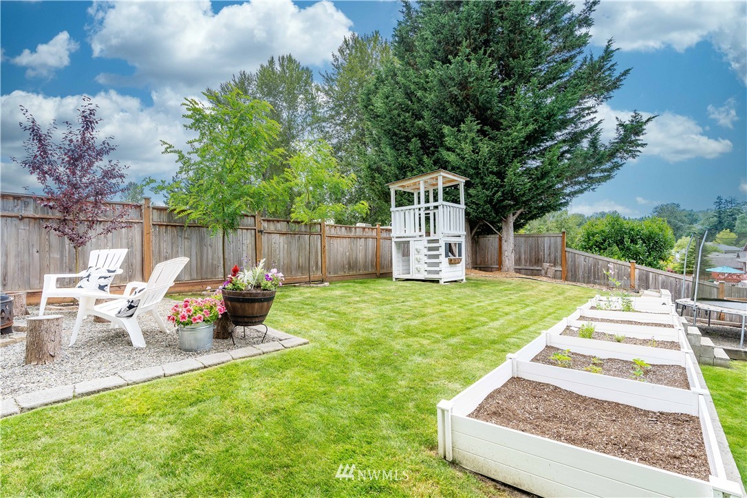 1128 235th Place Southwest Bothell, WA 98021 - Photo 21 of 22 a view of a backyard with table and chairs potted plants and a large tree