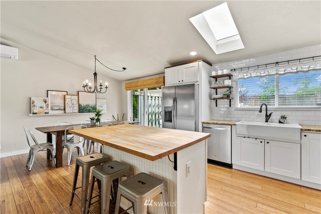 1128 235th Place Southwest Bothell, WA 98021 - Photo 6 of 22 a kitchen with stainless steel appliances kitchen island granite countertop a table chairs sink and cabinets