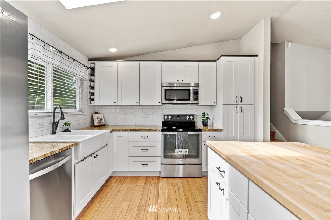 1128 235th Place Southwest Bothell, WA 98021 - Photo 7 of 22 a kitchen with a sink a counter top space stainless steel appliances and cabinets