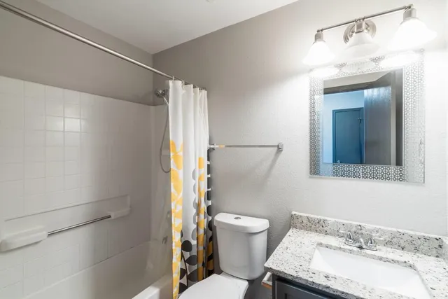 a bathroom with a granite countertop sink toilet and shower