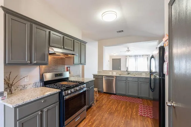 a kitchen with stainless steel appliances granite countertop a stove refrigerator and cabinets