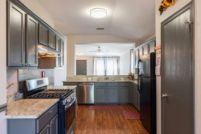 a kitchen with stainless steel appliances granite countertop a stove refrigerator and cabinets
