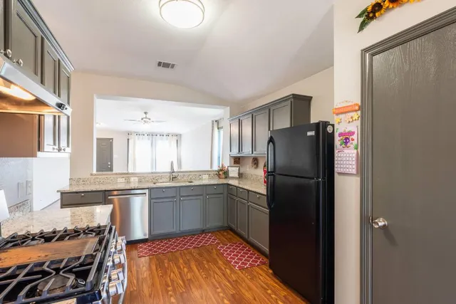a kitchen with stainless steel appliances granite countertop a refrigerator and a stove top oven