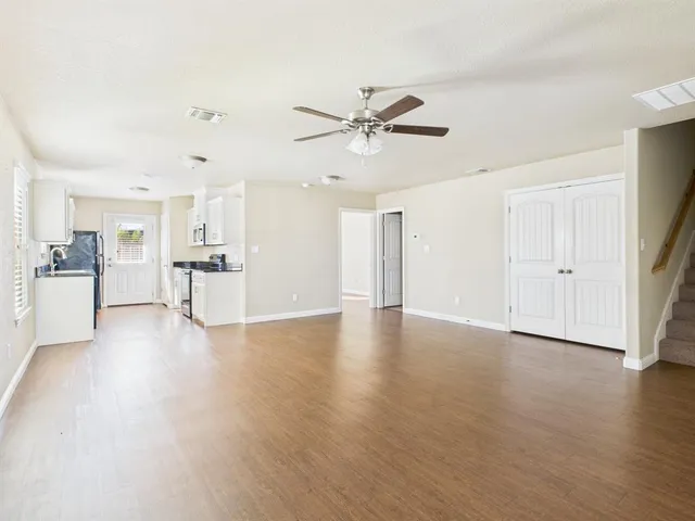 a view of a livingroom with wooden floor and a ceiling fan