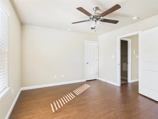 an empty room with wooden floor and ceiling fan