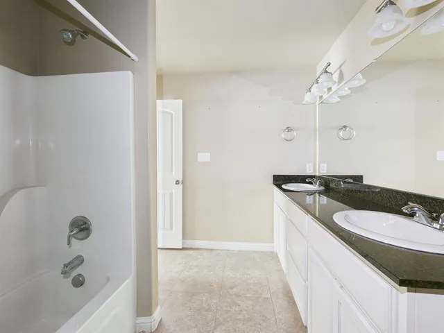 a bathroom with a granite countertop sink a mirror and a bathtub