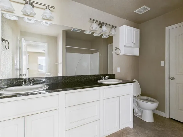 a bathroom with a granite countertop sink a toilet and mirror