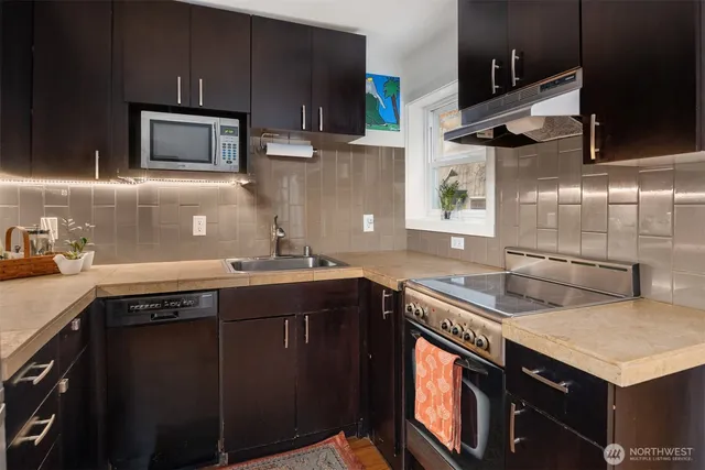 a kitchen with stainless steel appliances granite countertop a sink a stove and a microwave
