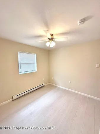 an empty room with windows and fan